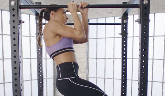 Femme réalisant une traction commando à la barre fixe dans une salle de street workout
